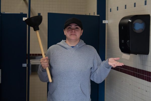 Head custodian Felicia Guadiana poses with plunger in Rocklin High bathroom