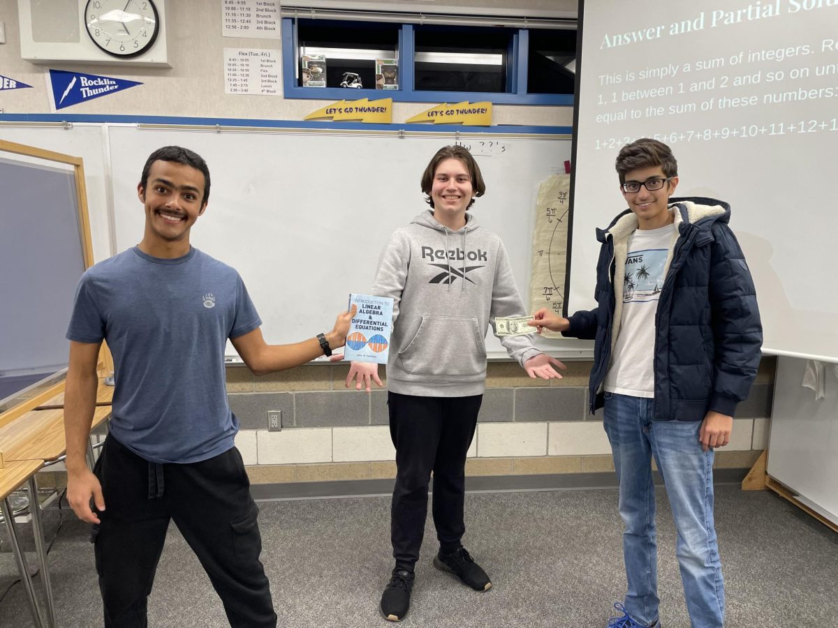 Integration bee winner Si Stagg, center, poses with contest organizers Mateo Lopez, left, and Rishabh Bhutani, right, with his prize of $100 and a textbook on March 1 in Mr. Trejos room.