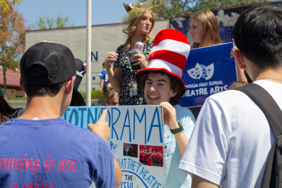 Roman Camber holds a sign for Drama Club.